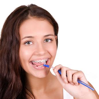 Girl demonstrating proper brushing and flossing with orthodontic braces